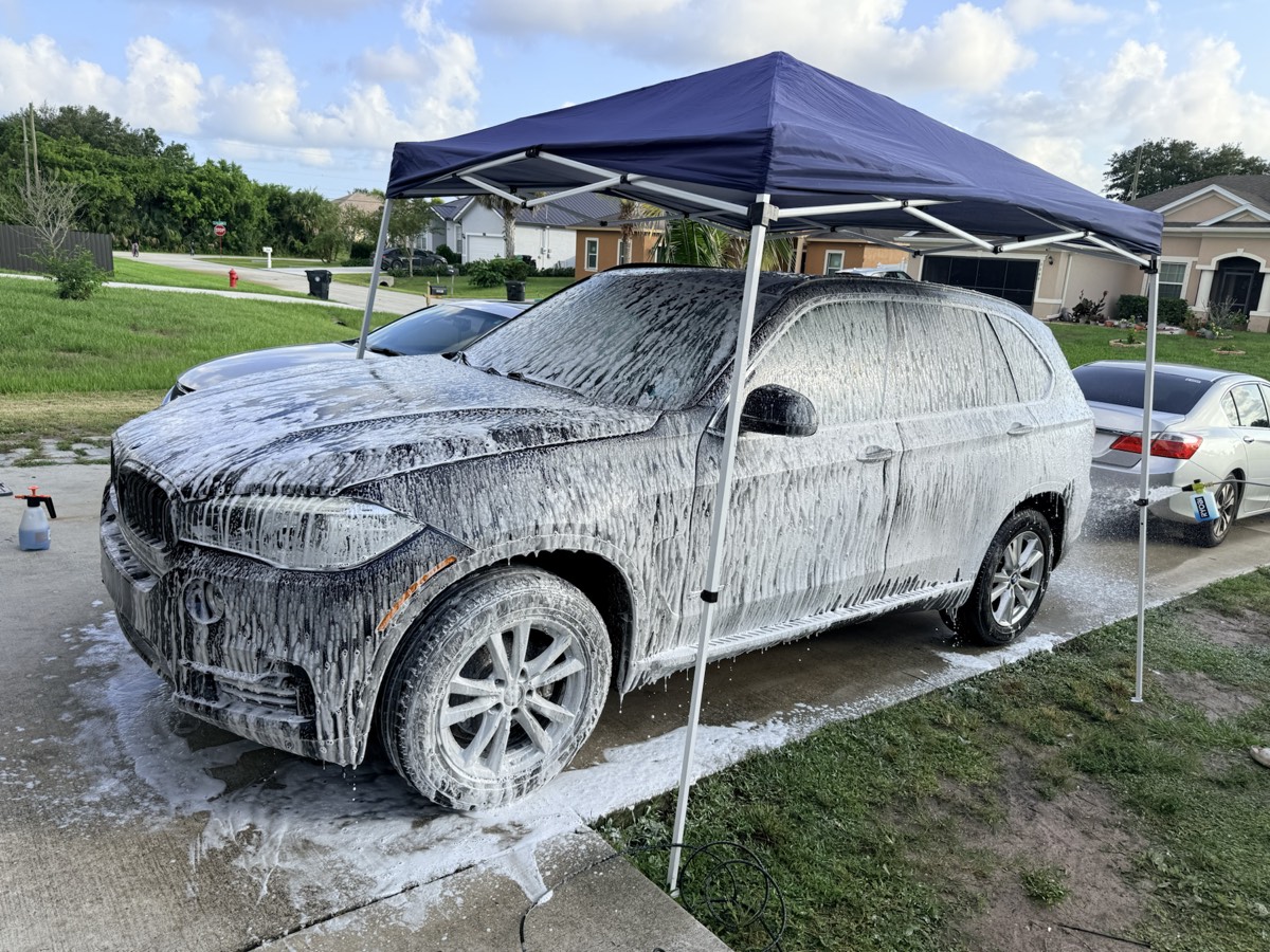 Black BMW covered in cleaning foam during a deep exterior wash